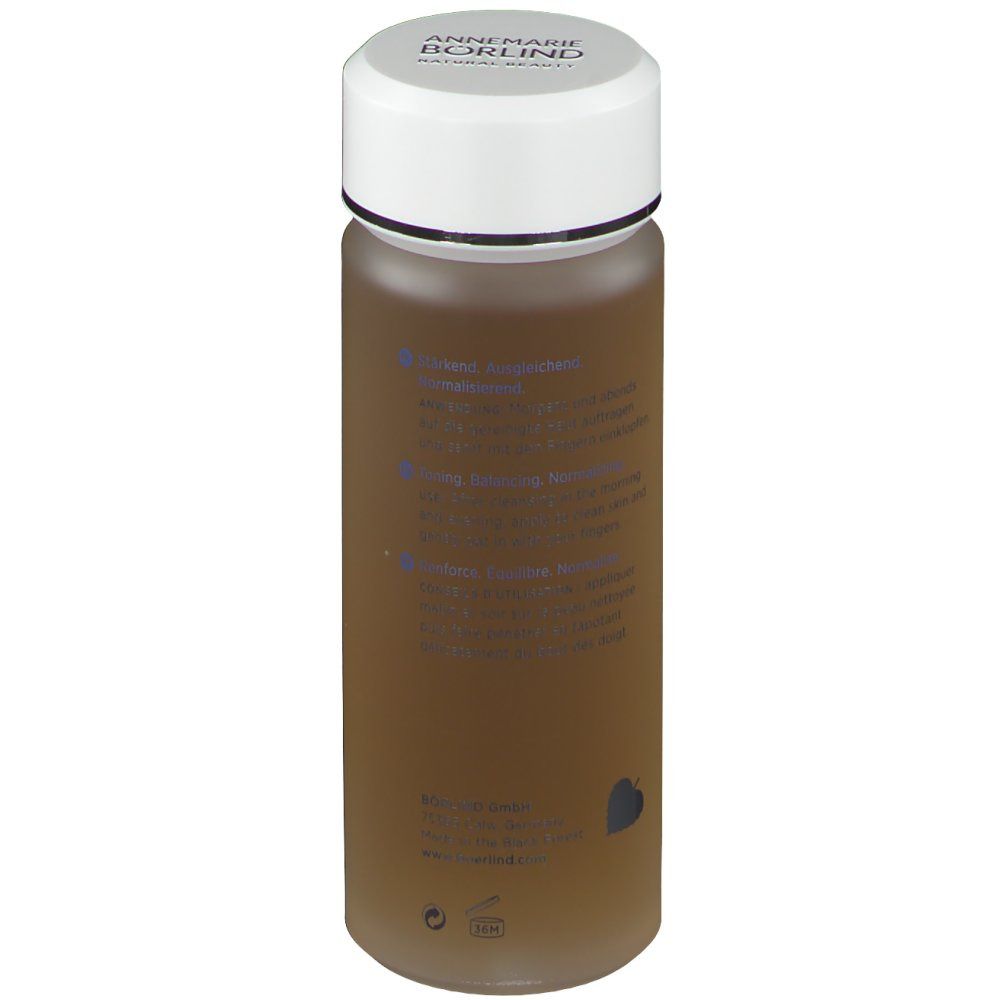 Zylindrische Flasche mit weißem Deckel. Aufschrift: ANNEMARIE BÖRLIND. Text in Deutsch, Englisch und Französisch. Braune Flüssigkeit.