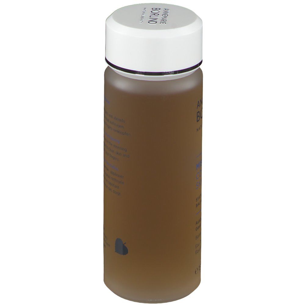 Zylindrische Flasche mit weißem Deckel. Aufschrift: ANNEMARIE BÖRLIND. Text in Deutsch, Englisch und Französisch. Braune Flüssigkeit.