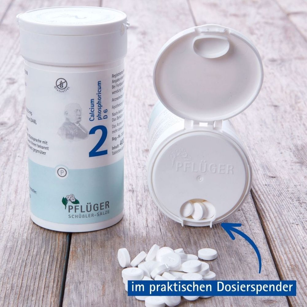 Geöffnete Dose mit Tabletten. Tabletten liegen daneben. Aufschrift: Calcium phosphoricum D6, Nummer 2. Pflüger-Logo.
