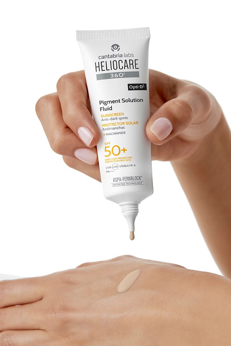 Hand hält HELIOCARE 360° Pigment Solution Fluid Sonnenschutz.