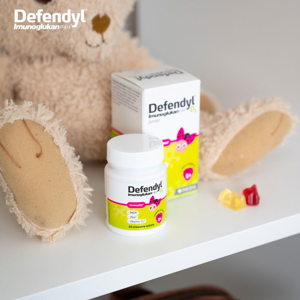 Flasche und Packung Defendyl-Imunoglukan P4H D₃. Teddybär und Gummibärchen. Auf weißem Regal.