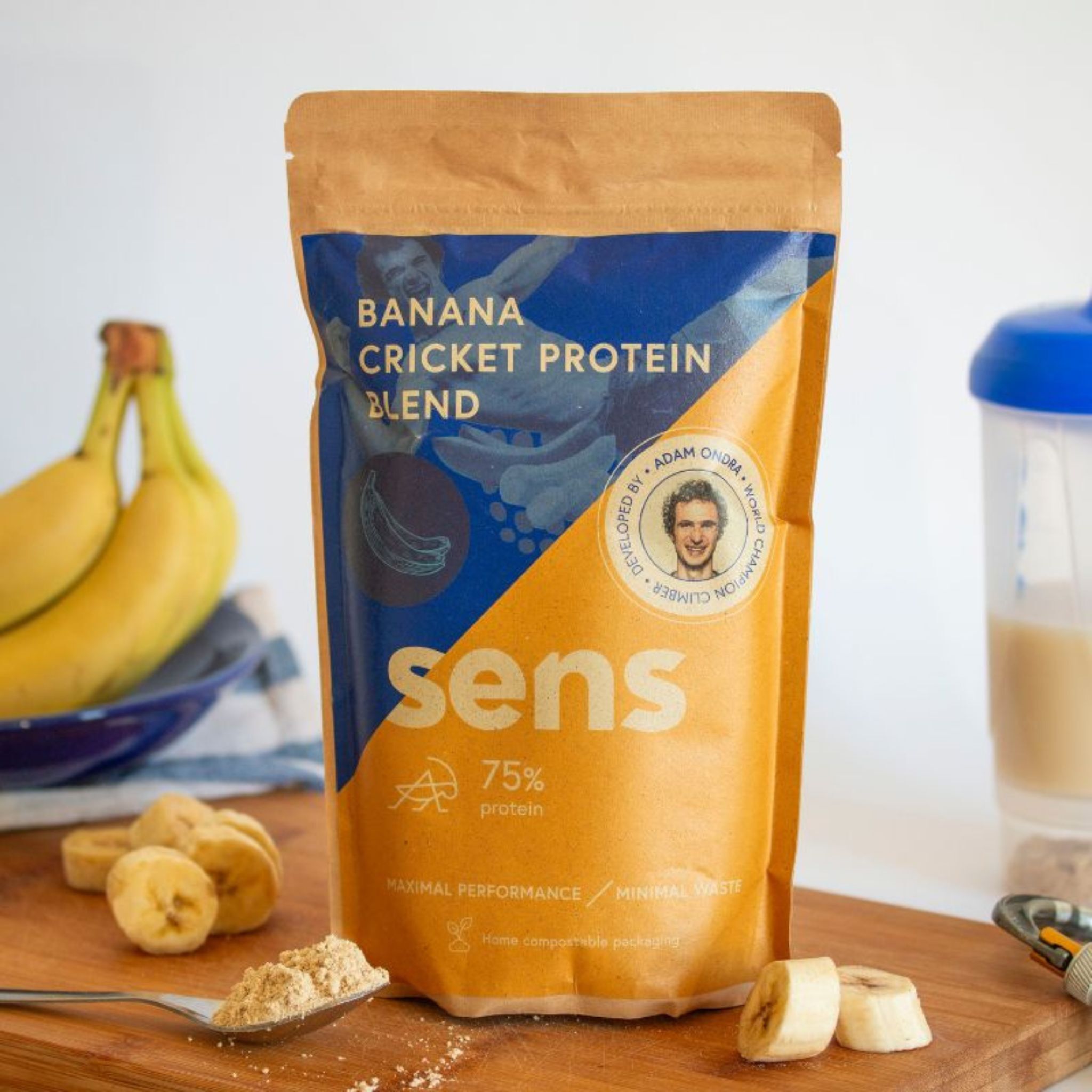 Sens Protein Shake Banane auf Holzbrett. Bananen, Pulver und Shaker daneben. Aufdruck: Banana Cricket Protein Blend.
