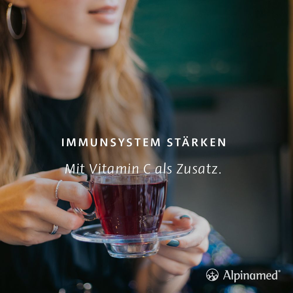 Frau hält eine Tasse Tee. Text: Immunsystem stärken. Mit Vitamin C als Zusatz. Alpinamed Logo.