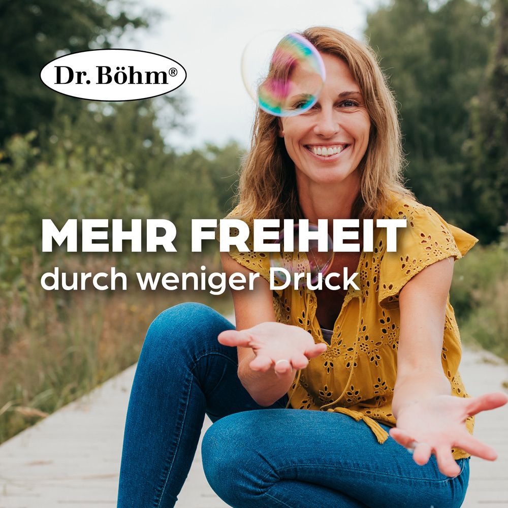 Lächelnde Frau im Freien, die Seifenblasen betrachtet. Text: Mehr Freiheit durch weniger Druck.