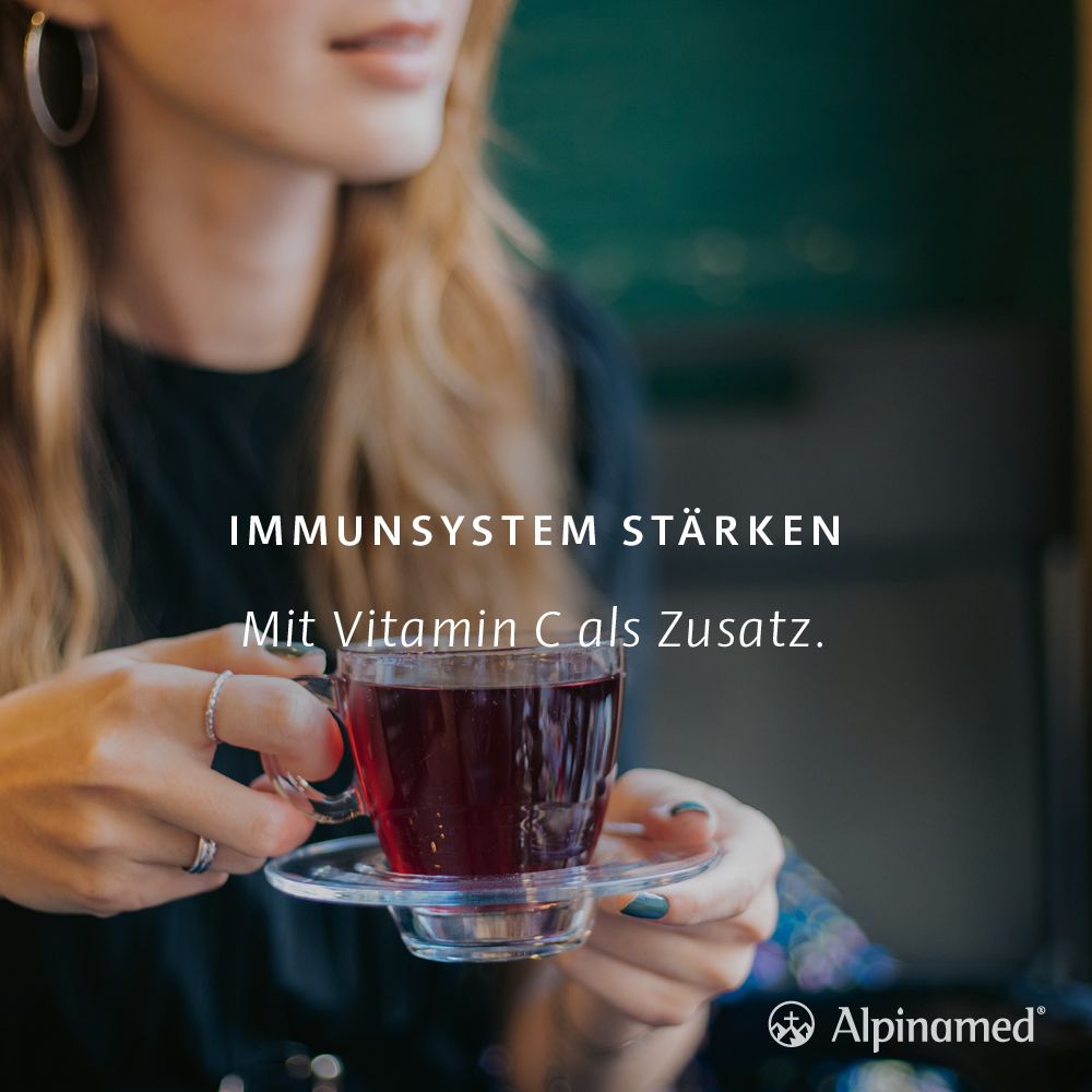 Frau hält eine Tasse Tee. Text: Immunsystem stärken. Mit Vitamin C als Zusatz. Alpinamed Logo.