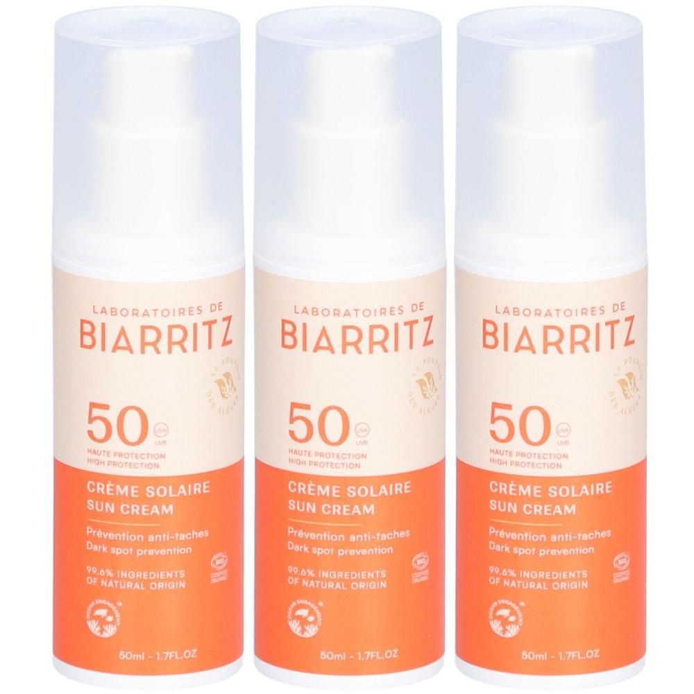 Drei Flaschen Sonnencreme. Weißer Deckel, orangefarbener Behälter. Aufschrift: BIARRITZ, 50, Crème Solaire, 99% Inhaltsstoffe natürlichen Ursprungs.