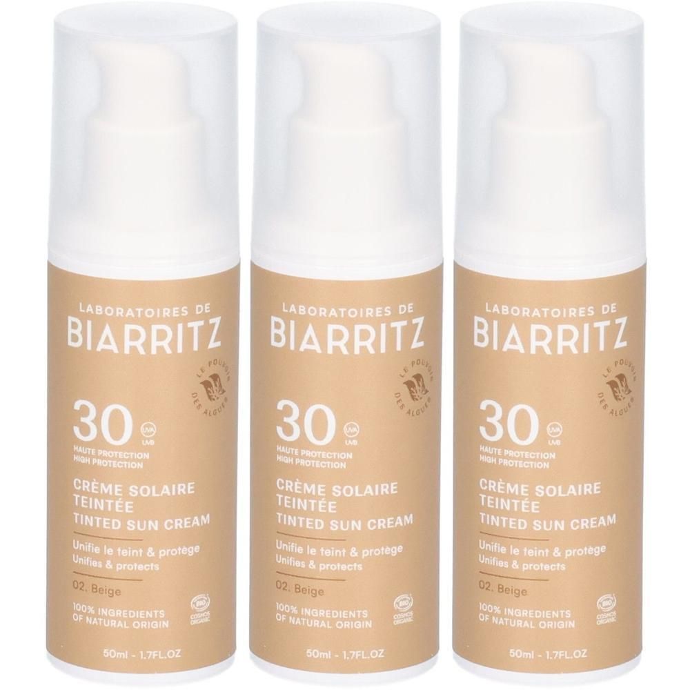 Drei Flakons getönter Sonnencreme. Aufschrift: LABORATOIRES DE BIARRITZ, 30, Crème Solaire Teintée, 02 Beige. Bio-Zertifizierung.