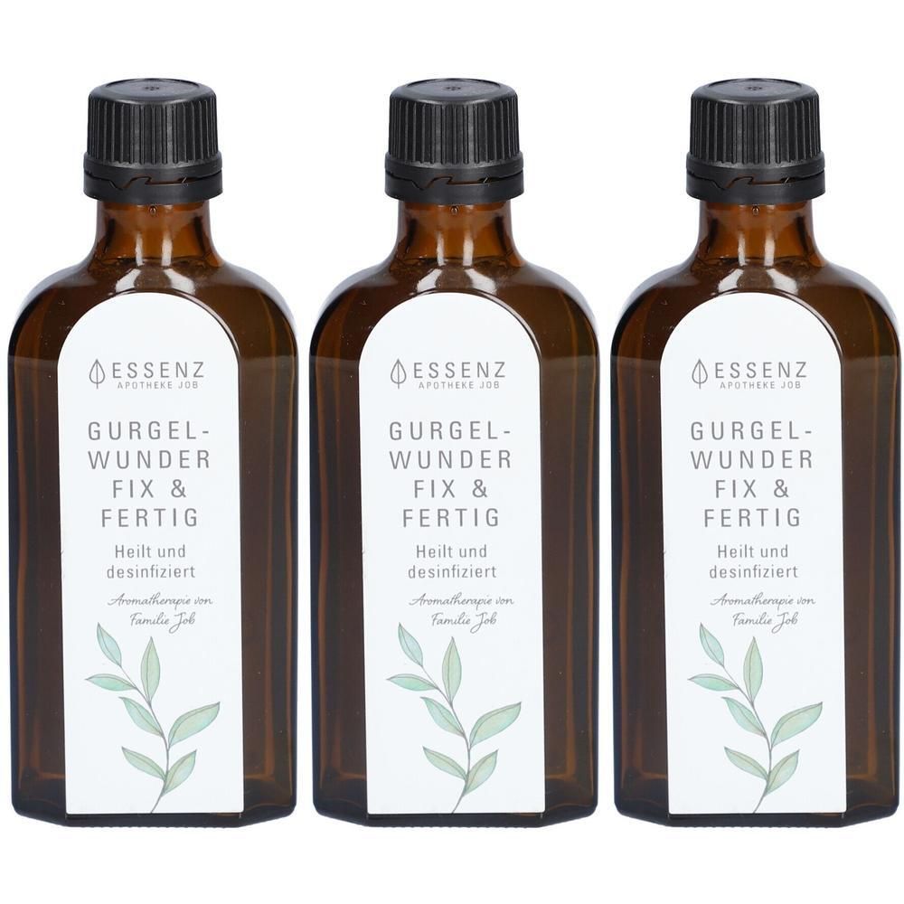 Drei braune Glasflaschen mit schwarzen Schraubverschlüssen. Weiße Etiketten mit grünen Zweigen und Text: 'ESSENZ APOTHEKE JOD GURGEL-WUNDER FIX & FERTIG Heilt und desinfiziert Aromatherapie von Familie Jod'.