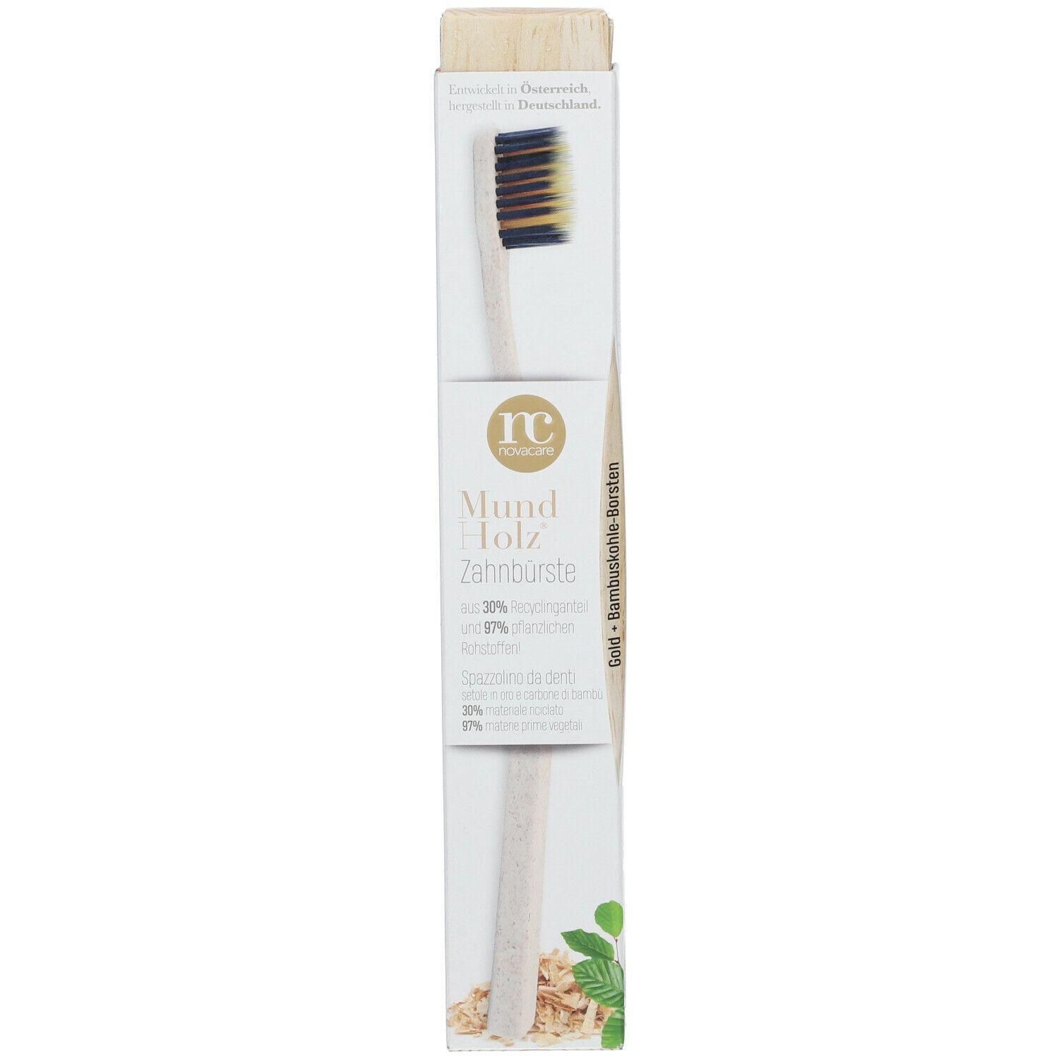 Zahnbürste in Verpackung. Holzgriff, schwarze und goldfarbene Borsten. Aufschrift: Mund Holz Zahnbürste.
