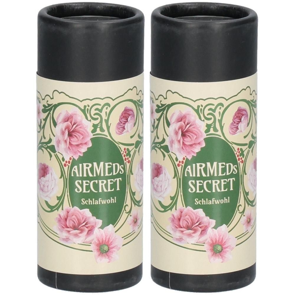 Zwei zylindrische Behälter mit schwarzem Deckel. Auf cremefarbenem Papier sind rosa Blüten und der Schriftzug AIRMEDS SECRET Schlafwohl abgebildet.