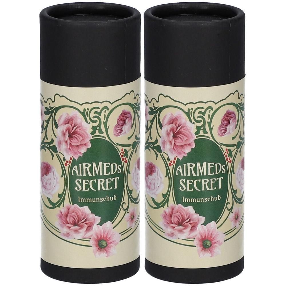 Zwei zylindrische Behälter mit schwarzem Deckel. Aufschrift: AIRMEDS SECRET Immundschub. Blumenmuster.