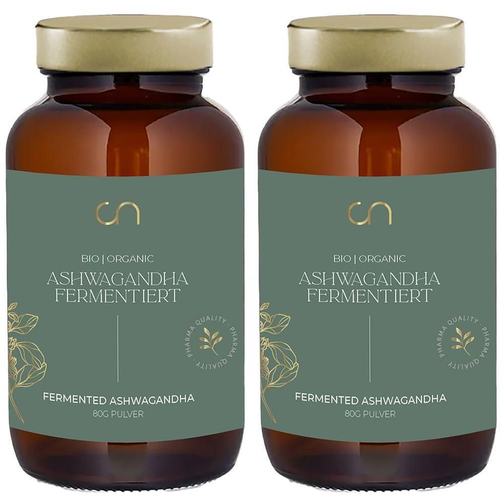 Zwei braune Glasflaschen mit goldenen Deckeln. Auf den Etiketten steht "ASHWAGANDHA FERMENTIERT". Das Logo "cn" ist sichtbar. Grün-goldenes Design.