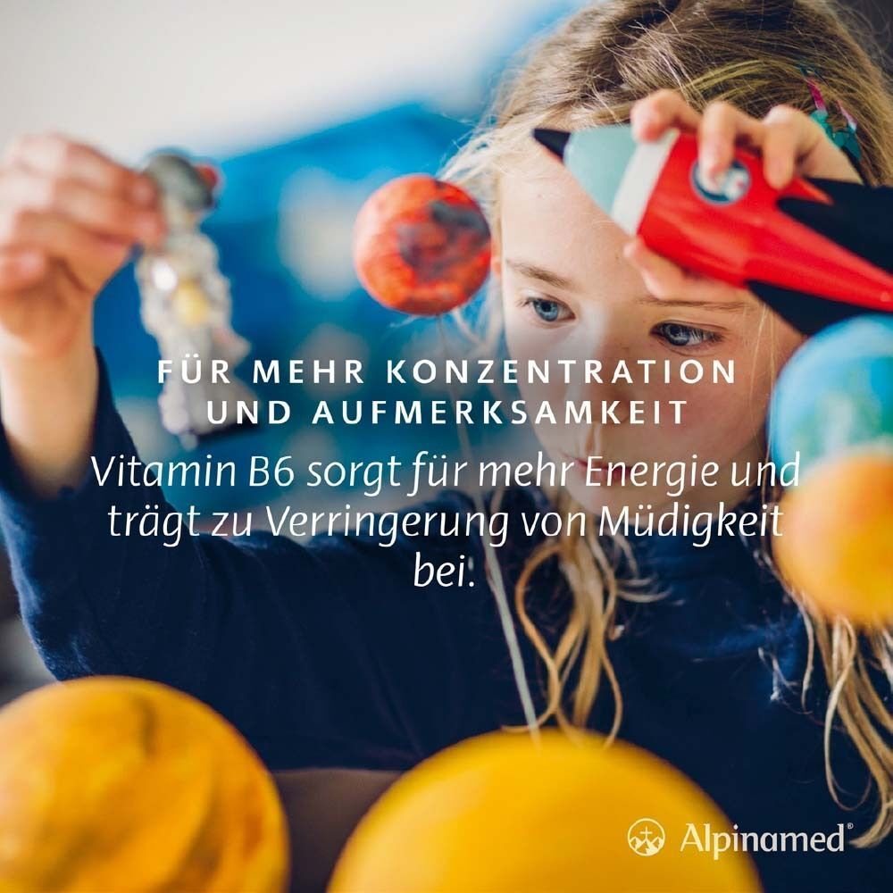 Ein Mädchen spielt mit Planeten. Text: Für mehr Konzentration und Aufmerksamkeit. Vitamin B6 sorgt für mehr Energie und trägt zur Verringerung von Müdigkeit bei.