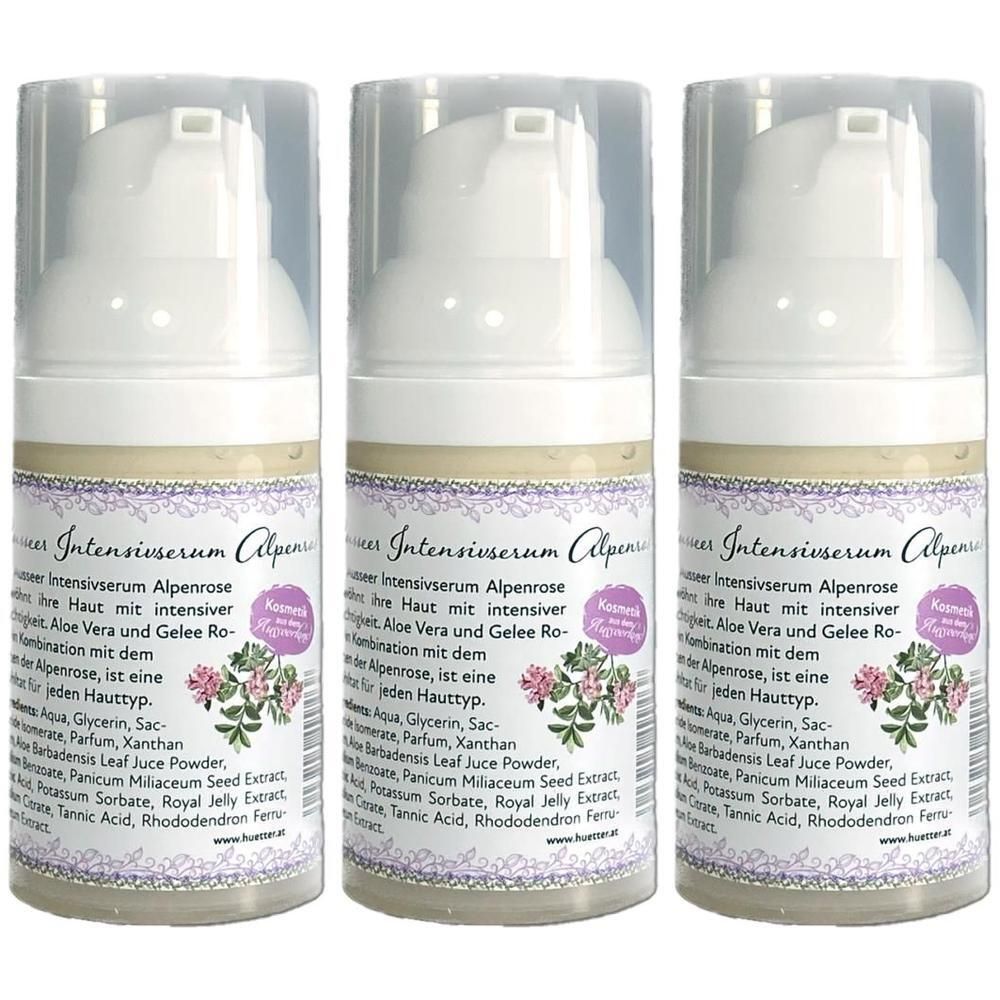 Drei Flaschen Ausseer Intensivserum Alpenrose. Weiße Pumpflaschen mit transparenten Kappen und Etiketten mit Text und floralem Motiv.