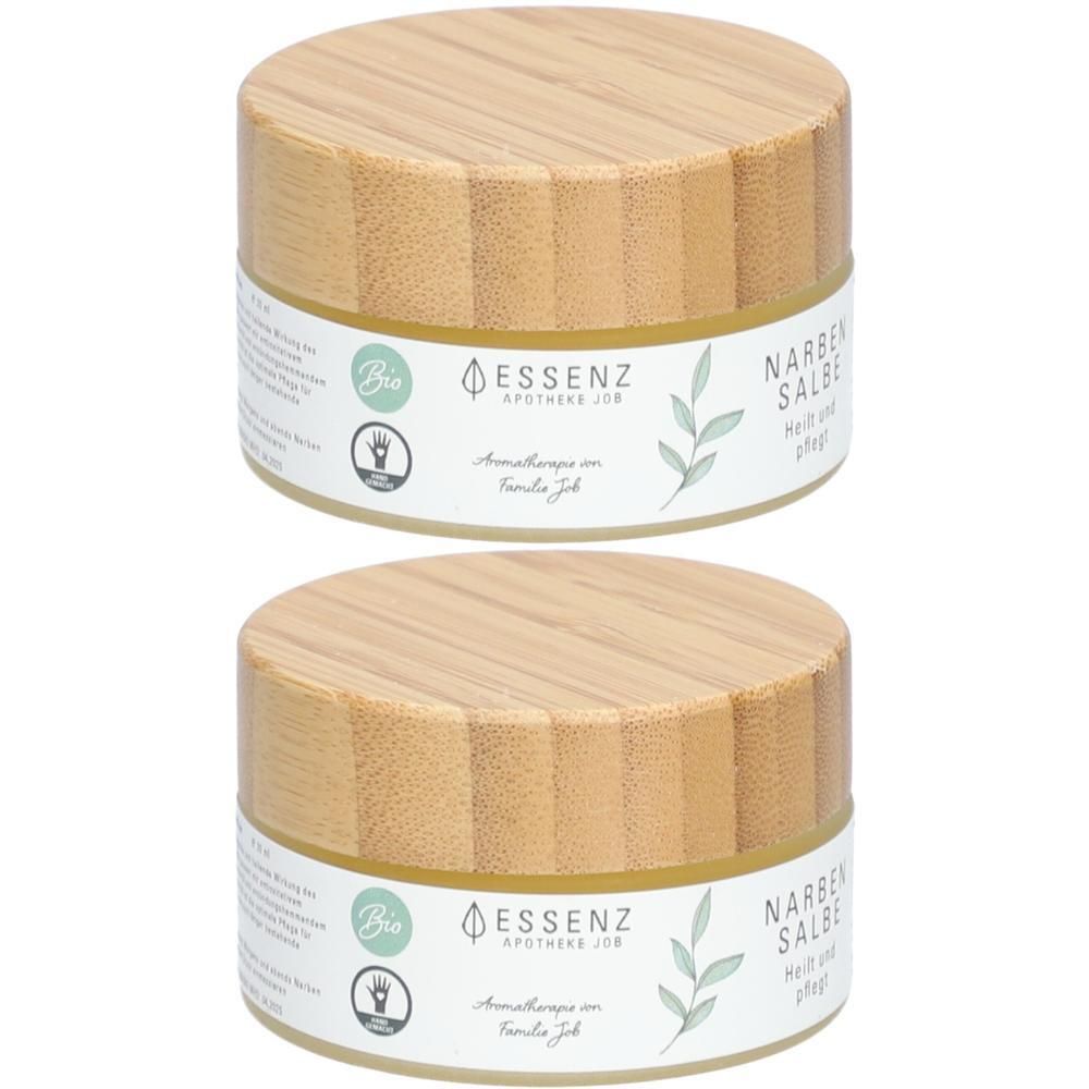 Zwei runde Tiegel mit Holzdeckel, beschriftet mit 'Essenz Narbensalbe'.