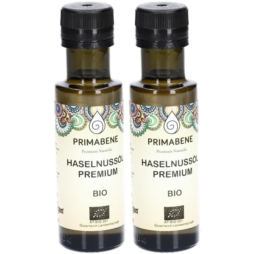 Zwei Glasflaschen mit schwarzem Verschluss. Auf den Etiketten steht "PRIMABENE", "HASELNUSSÖL PREMIUM BIO" und ein Bio-Siegel.