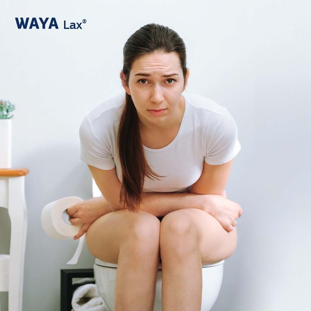 Frau sitzt auf Toilette, hält Toilettenpapier. Gesichtsausdruck: besorgt. Keine WAYA Lax® Produkte sichtbar.
