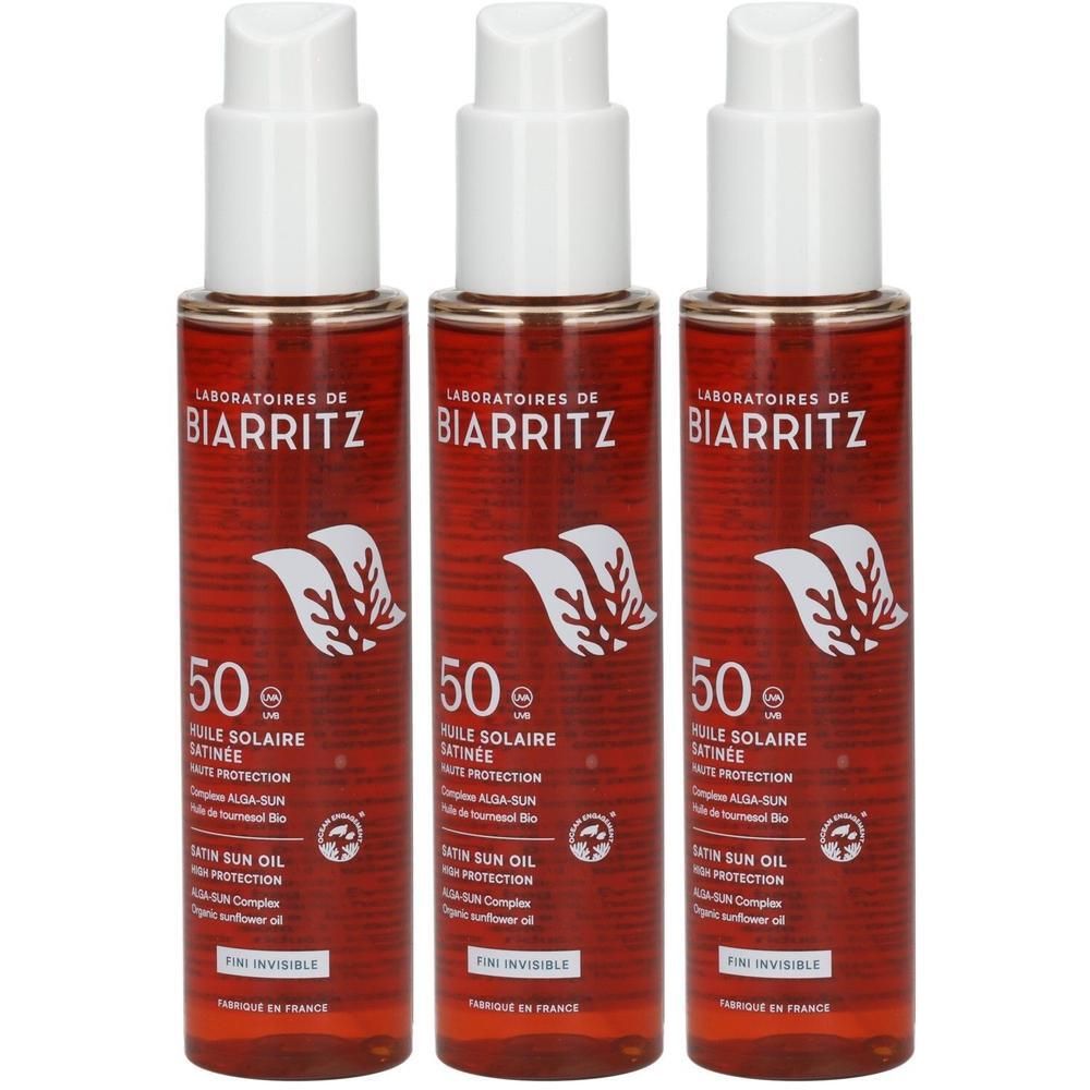 Drei Flaschen Laboratoires de Biarritz Sonnenschutzöl LSF 50 mit Pumpspendern. Rote Flaschen mit weißem Etikett und Blattmotiv.