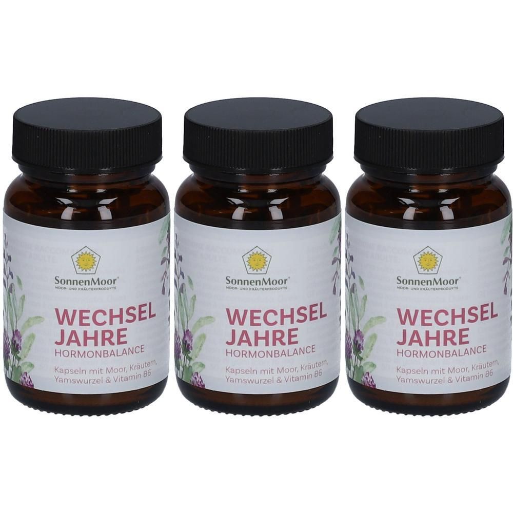 Drei braune Flaschen mit SonnenMoor Wechseljahre Hormonbalance Kapseln. Jede Flasche hat einen schwarzen Deckel und ein weißes Etikett mit Produktinformationen und Kräutern.