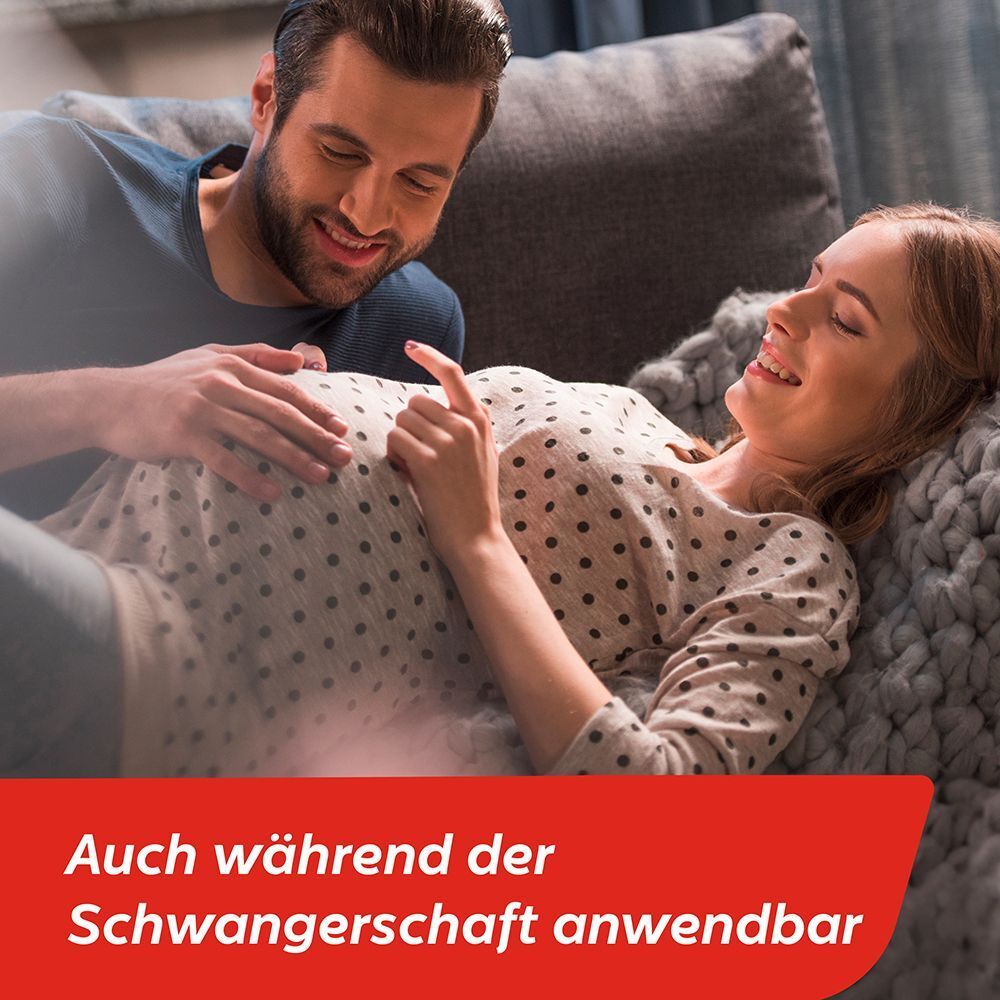 Ein Paar schaut lächelnd auf den Bauch einer schwangeren Frau.