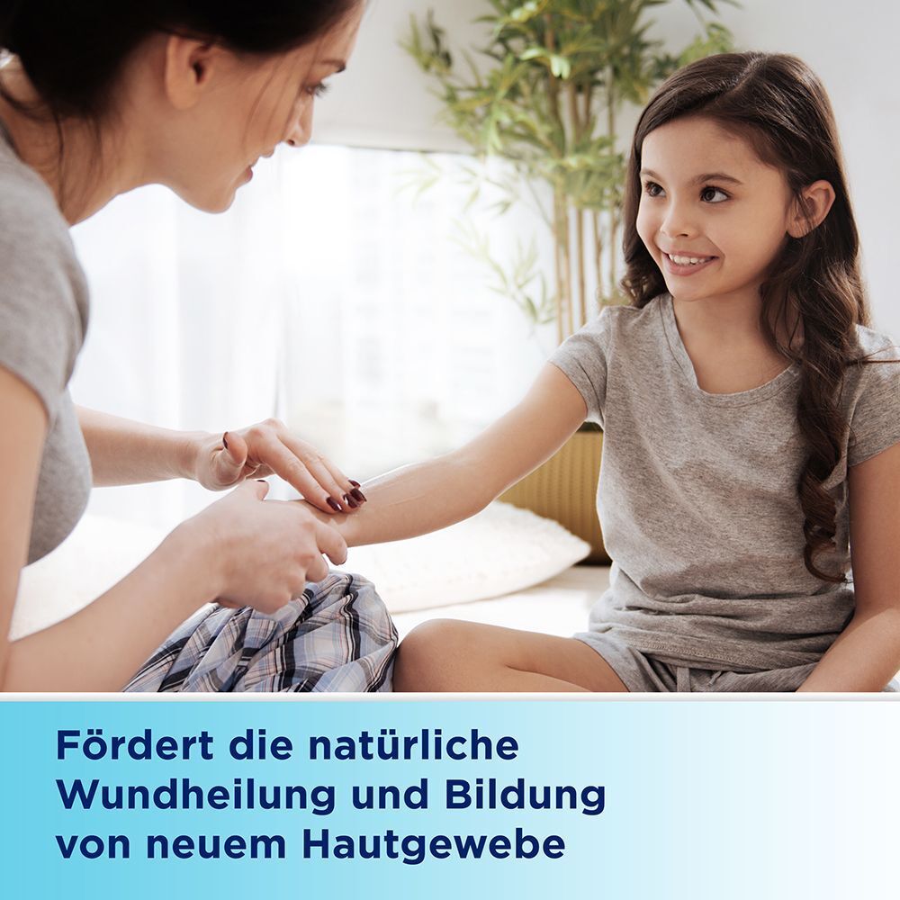Mutter trägt Salbe auf die Armwunde ihrer Tochter auf.