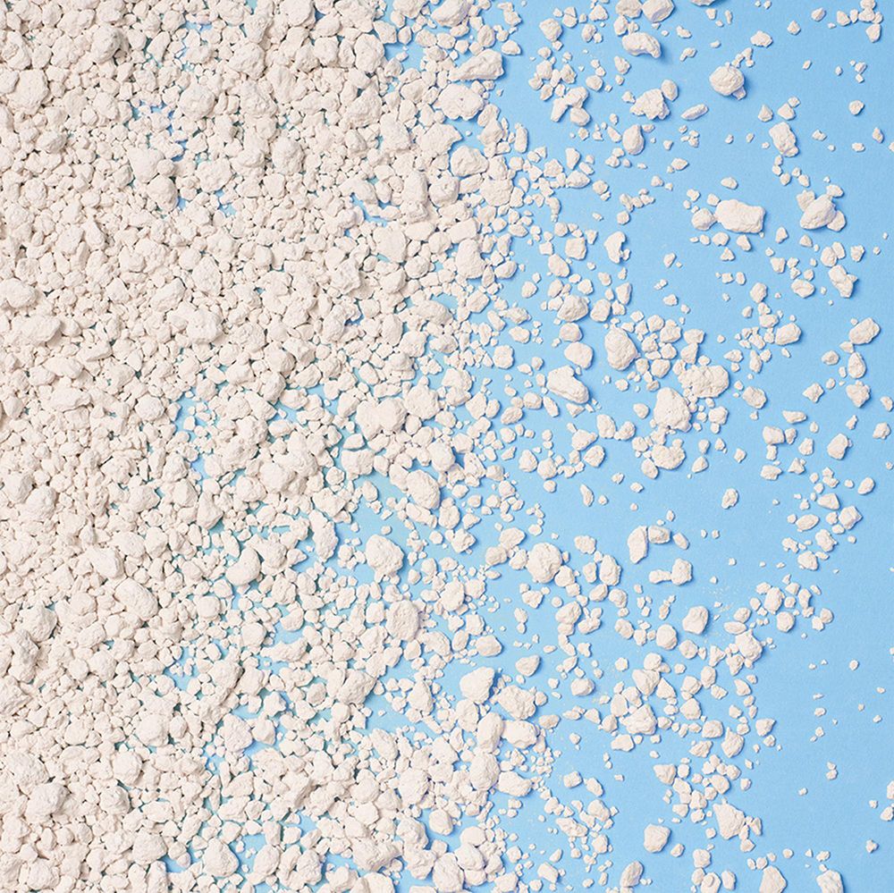 Nahaufnahme von CATSAN Hygiene Plus Katzenstreu-Granulat auf blauem Hintergrund.