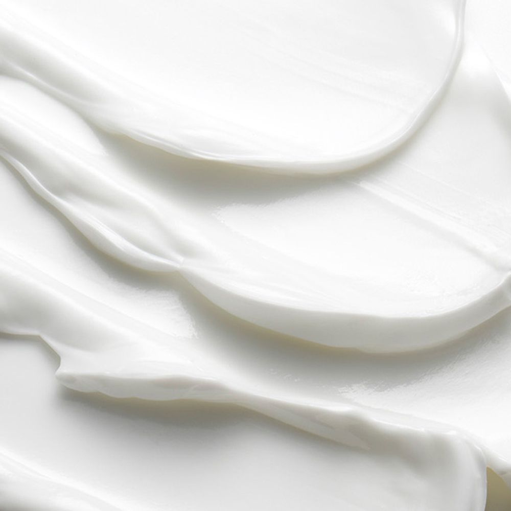 Nahaufnahme einer weißen Creme. Die Creme ist glatt und hat eine wellenförmige Textur.