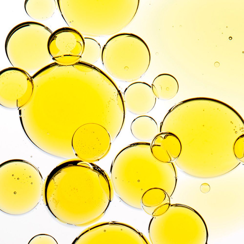 Nahaufnahme von gelben Ölblasen auf weißem Hintergrund. Verschiedene Größen und Formen.