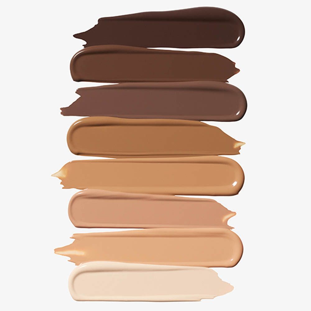 Acht streifenförmige Proben von flüssigem Make-up in verschiedenen Hauttönen, von dunkelbraun bis hellbeige.
