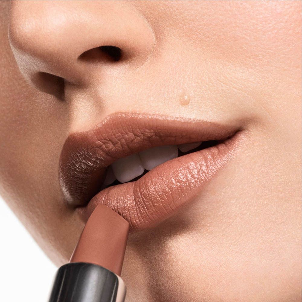 Ein Lippenstift in einem silbernen Gehäuse wird auf die Lippen einer Person aufgetragen.