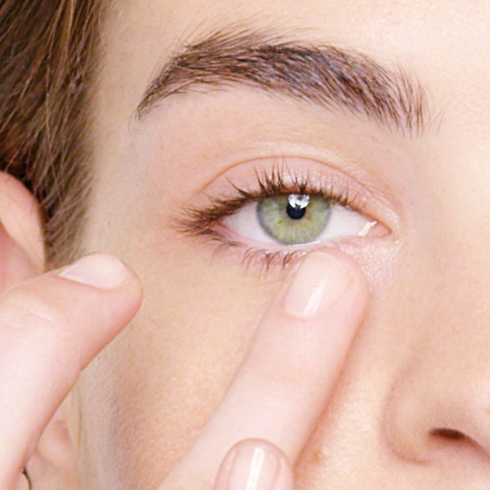 Nahaufnahme eines Auges, Finger berühren sanft die Haut unter dem Auge.