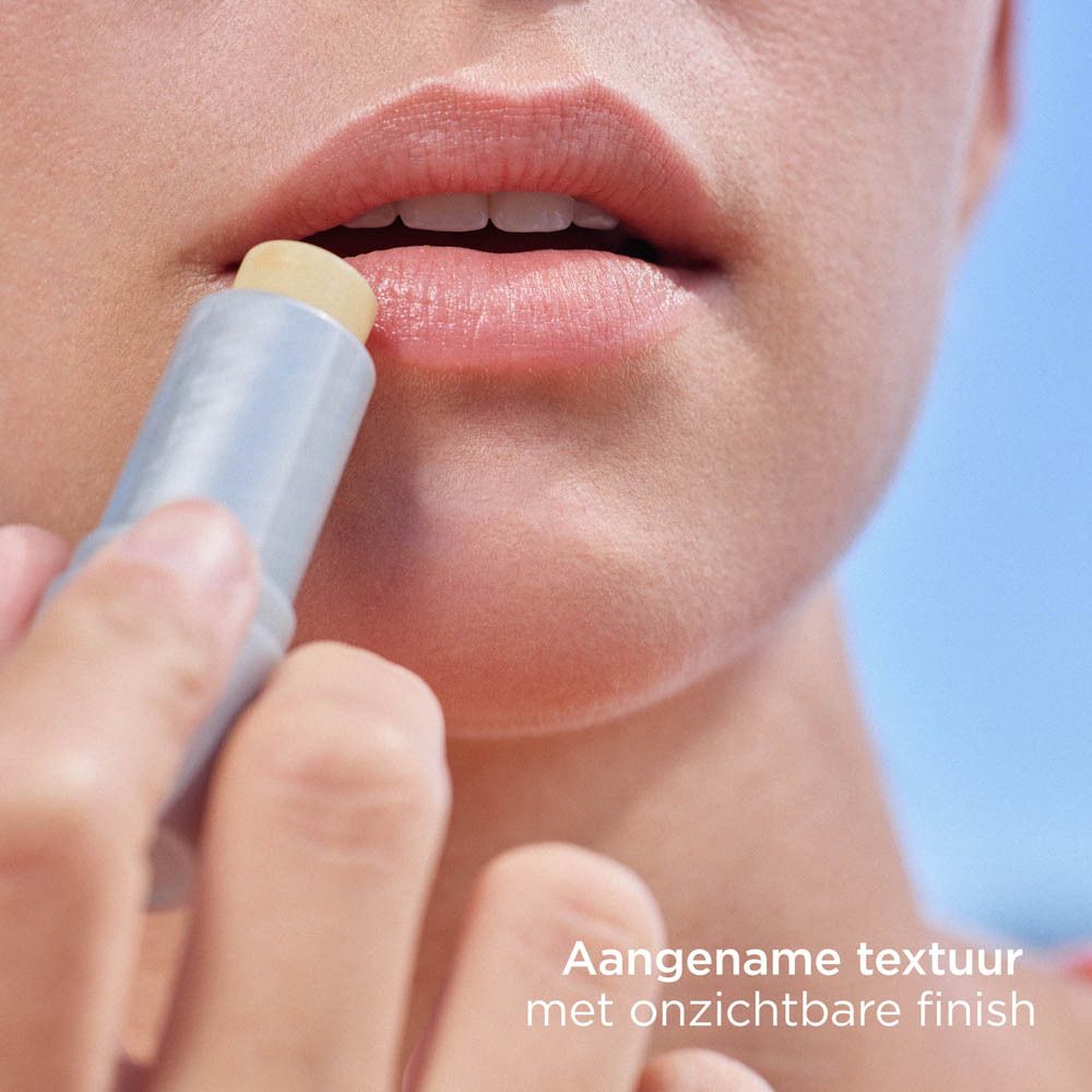 Lippen mit Lippenbalsam-Stift. Der Stift wird aufgetragen. Text: Angenehme Textur mit unsichtbarem Finish.