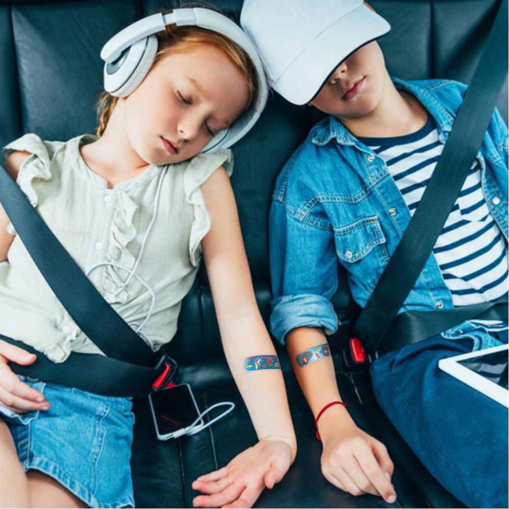 Zwei Kinder mit Pflastern auf den Armen. Pflaster mit Comic-Motiven. Kinder sitzen angeschnallt im Auto.