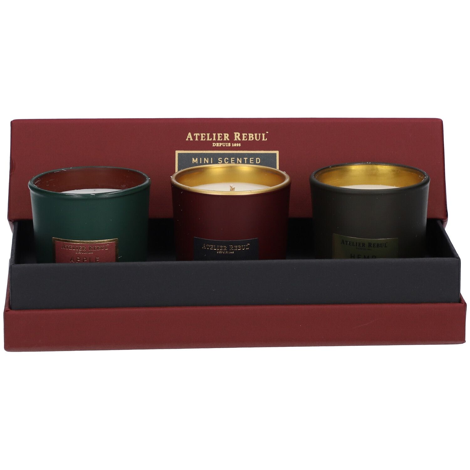 Geöffnete Schachtel mit drei Mini-Duftkerzen. Grüne, rote und dunkelgrüne Kerzen mit goldenen Rändern.