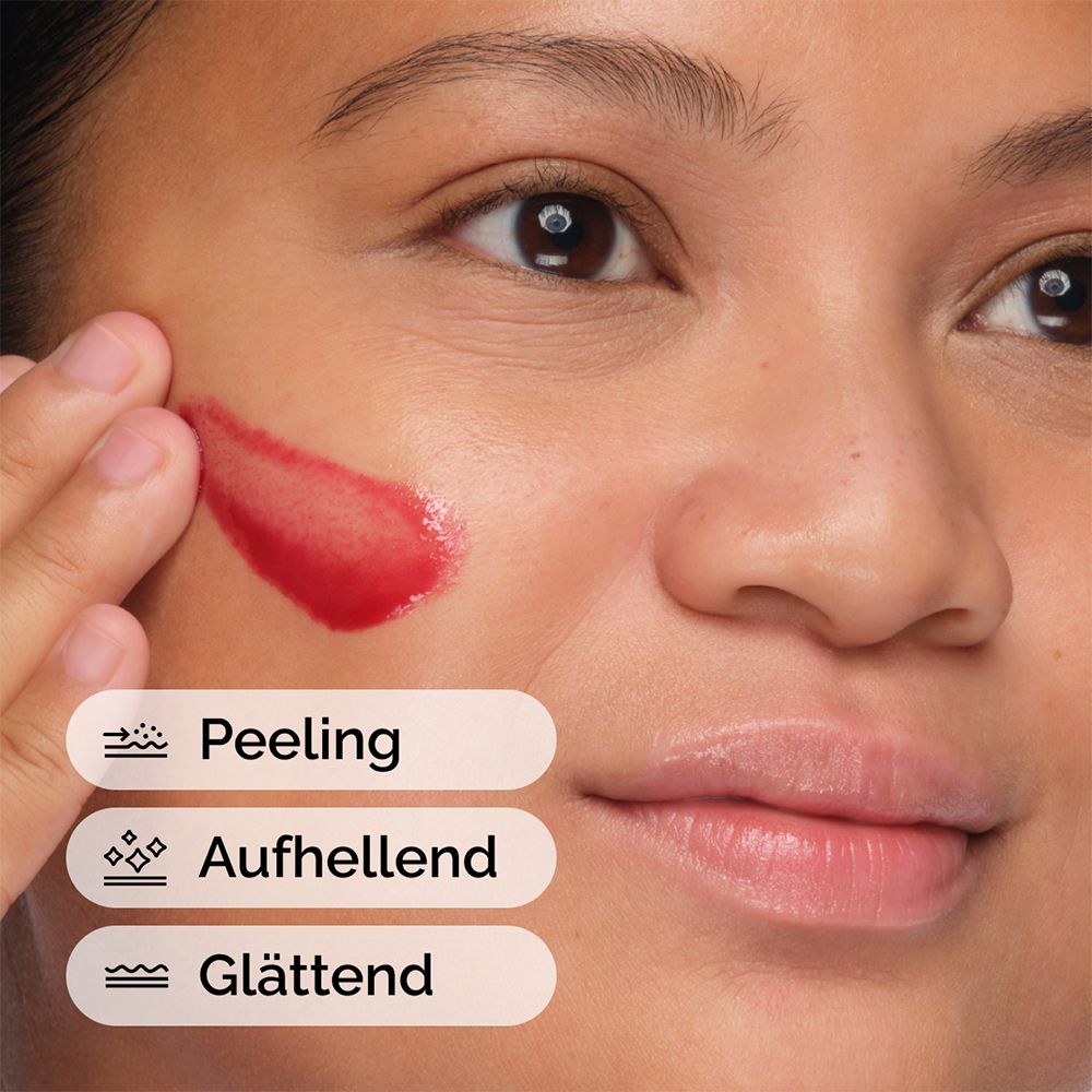 Person trägt rote Flüssigkeit auf das Gesicht auf. Text: Peeling, Aufhellend, Glättend.