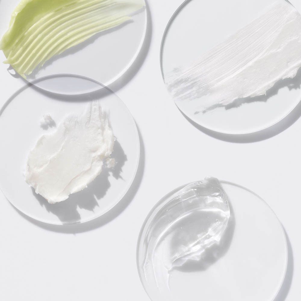 Vier Proben von Hautpflegeprodukten: eine grüne Creme, eine weiße Creme, eine weiße Paste und ein klares Gel.