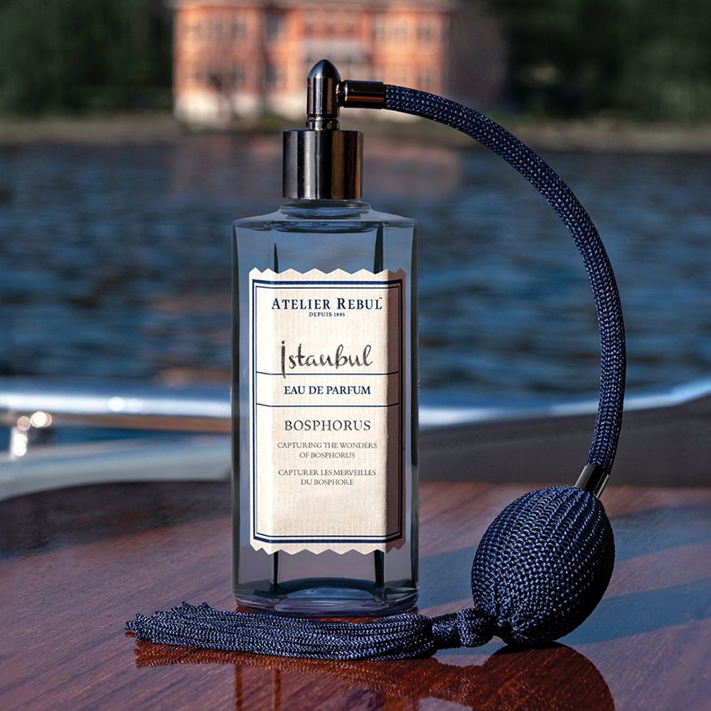 Dunkelblaue Flasche mit Zerstäuber und Quaste. Aufschrift: Istanbul Bosphorus Eau De Parfum. Hintergrund: Wasser.