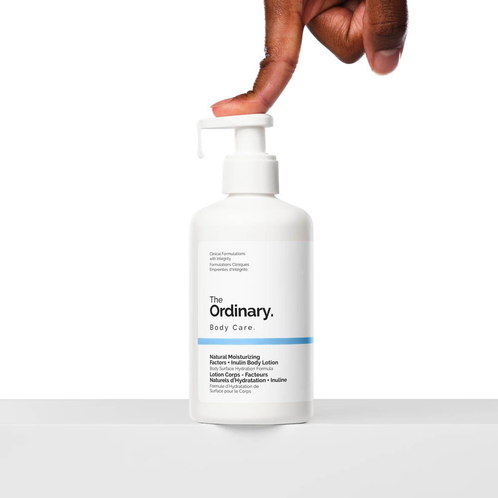 Weiße Flasche mit Pumpe. Hand drückt auf den Spender. Aufschrift: The Ordinary, Body Care.