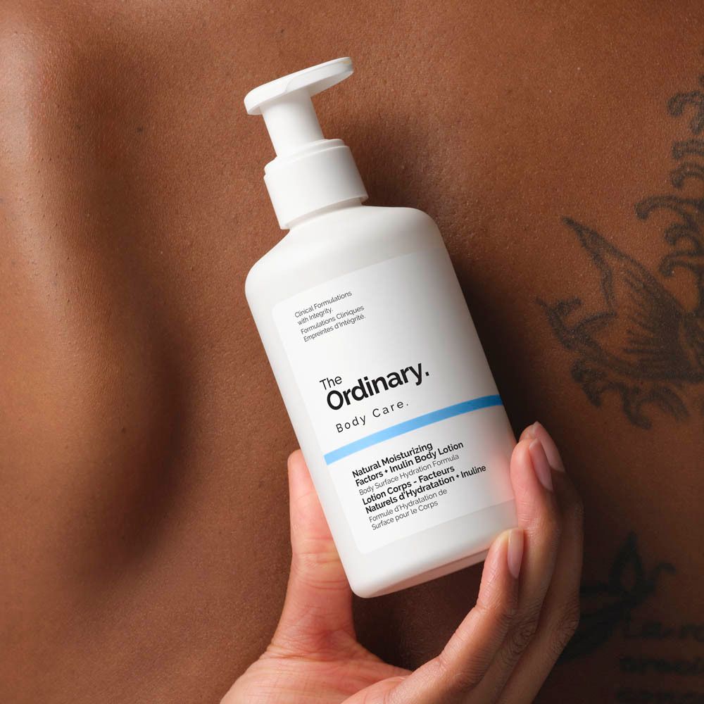 Weiße Flasche mit Pumpe. In der Hand gehalten. Aufschrift: The Ordinary, Body Care, Natural Moisturizing Factors + Inulin Body Lotion.