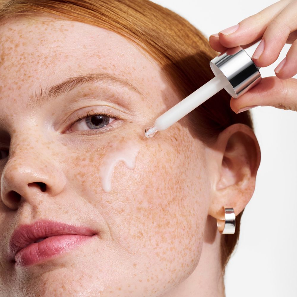 Frau mit Sommersprossen, Serum wird mit Tropfer aufgetragen. Tropfer mit silbernem Hals.