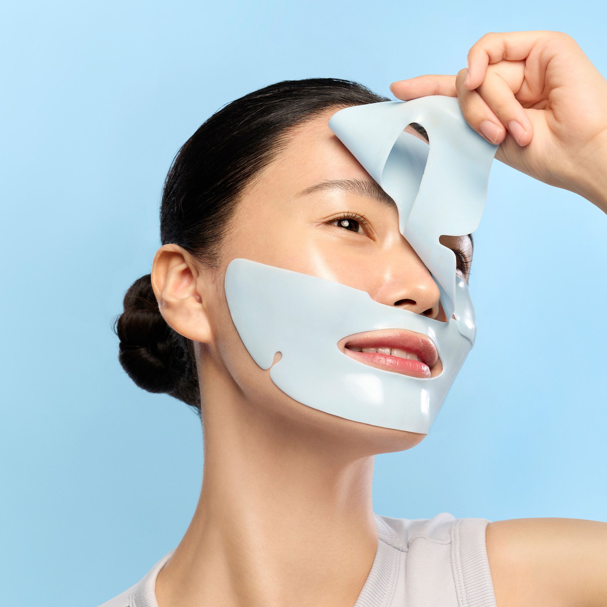 Person hält eine blaue Gesichtsmaske. Maske mit Augen- und Mundöffnungen. Auf blauem Hintergrund.
