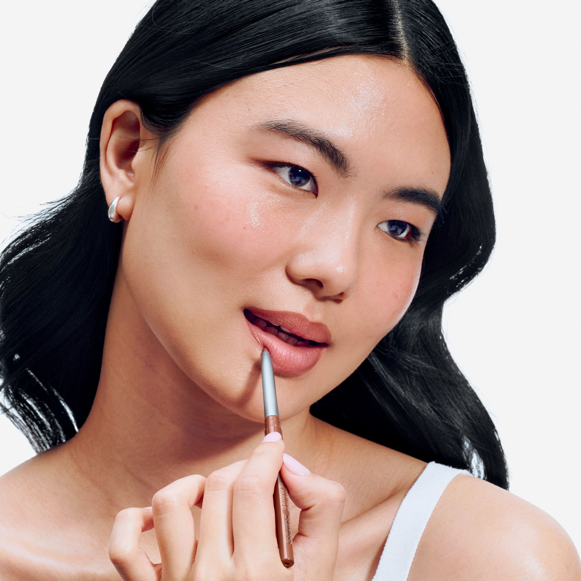 Nahaufnahme einer Frau, die ihre Lippen mit einem braunen Lipliner umrandet. Der Lipliner ist von Clinique.