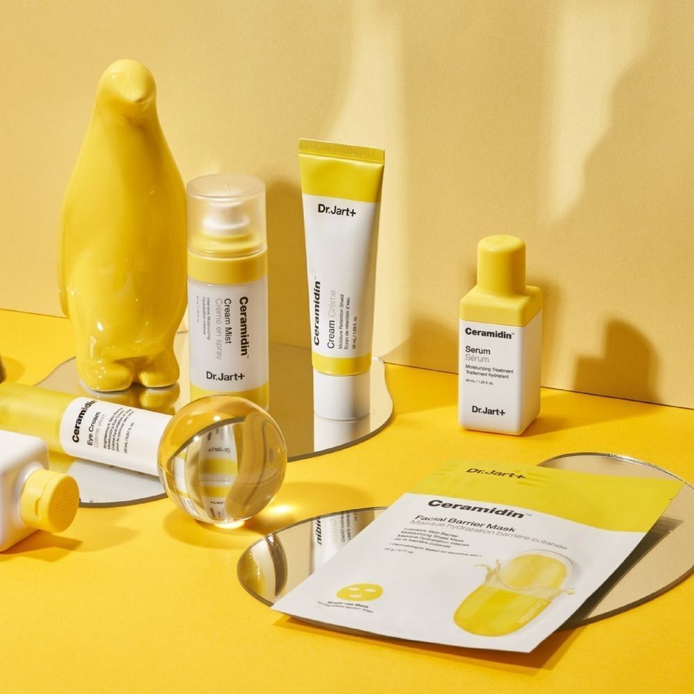 Gelber Hintergrund mit Dr.Jart+ Ceramidin Produkten. Enthalten: Maske, Creme, Serum, Nebel und Dekoration.