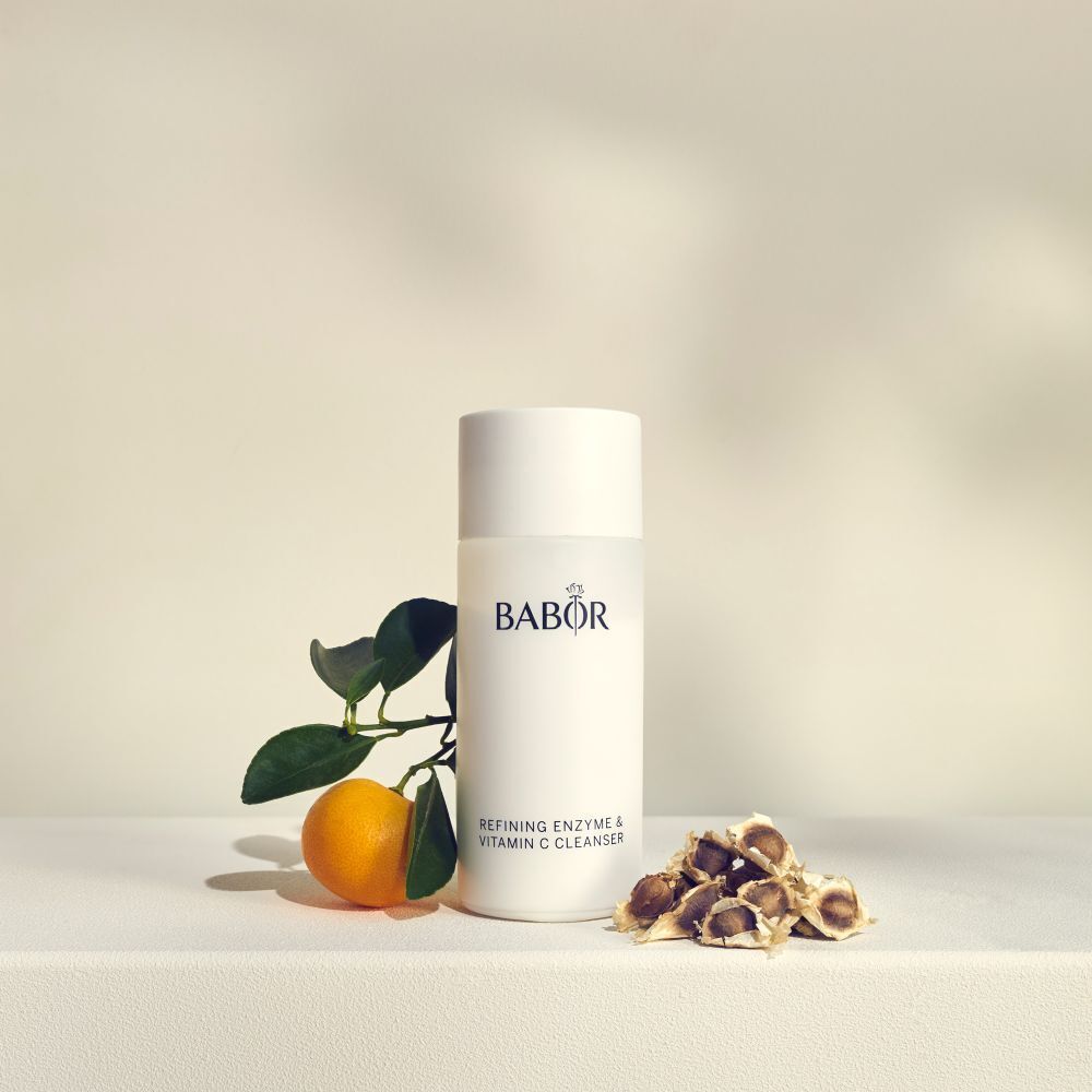 Weiße Flasche mit BABOR-Logo und Text: Refining Enzyme & Vitamin C Cleanser. Mit Orange und Blättern.