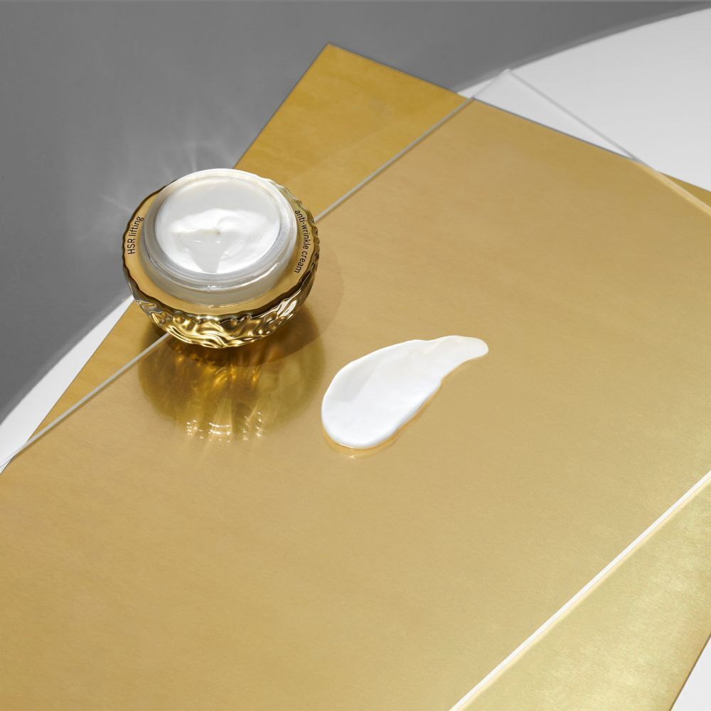 Babor HSR Lifting Cream Tiegel mit einer Probe der Creme daneben auf goldener Oberfläche.