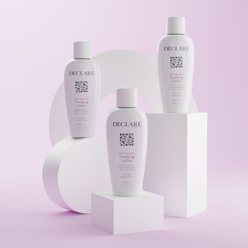 Drei weiße Flaschen mit Deckel auf Podesten. Aufschrift: DECLARÉ, Logo, Toning Lotion. Hintergrund: Weiß und Rosa.