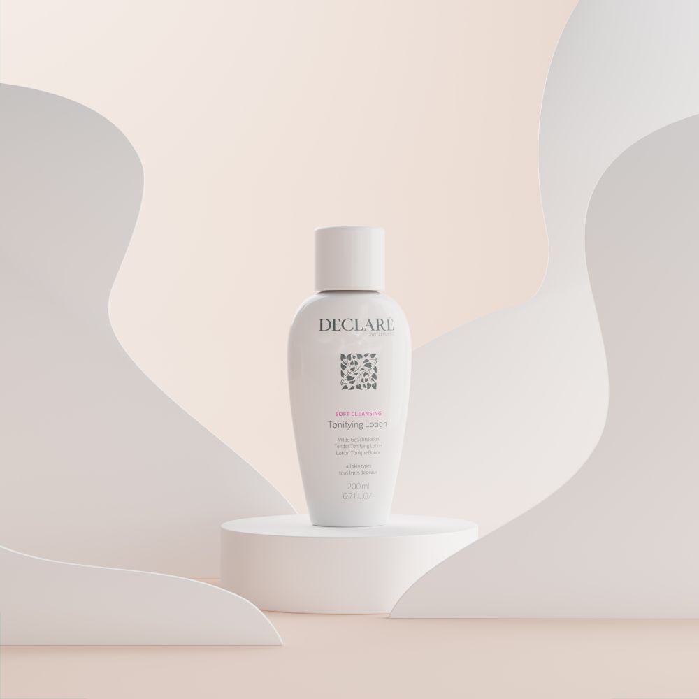 Weiße Flasche DECLARÉ Toning Lotion auf Podest. Aufschrift: Soft Cleansing, Toning Lotion. Hintergrund: weiße Formen.