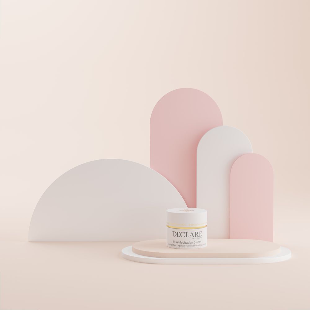 Creme-Tiegel auf Podest. Hintergrund mit weißen und rosa Elementen. Aufschrift: DECLARÉ Skin Meditation Cream.