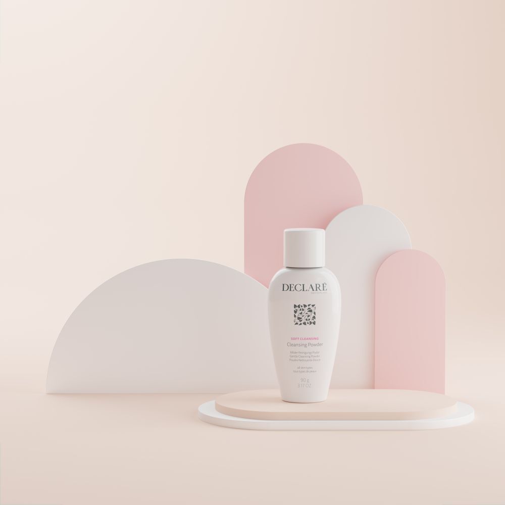 Declare Softcleansing Cleansing Powder auf Podest. Weiß, Logo, Produktbezeichnung. Rosa und weiße Formen im Hintergrund.