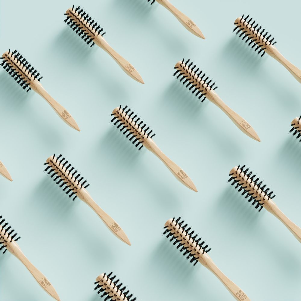 Mehrere Stylingbürsten auf hellblauem Hintergrund. Holzgriff, schwarze Borsten. MARLIES MÖLLER.
